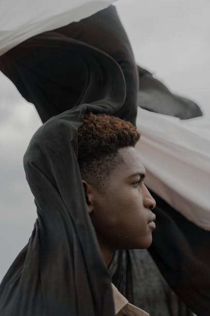 Side profile of a man with black and white fabric in an outdoor setting.