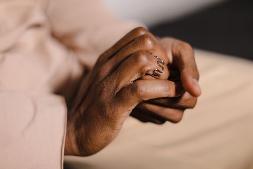 Free Elegant close-up of clasped hands featuring a serpentine ring on a finger. Stock Photo