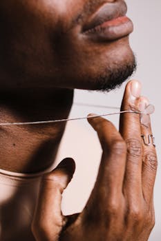Artistic close-up of a man's hand with a silver ring and necklace, highlighting jewelry details.