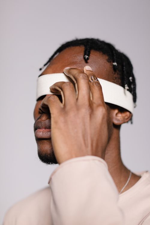 Free A black man with eyes covered by a white band in an indoor studio setting. Stock Photo