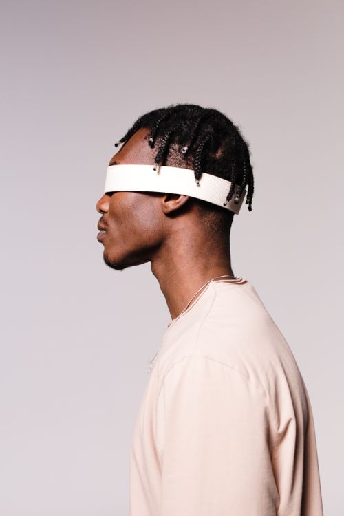 Free Side view of a blindfolded man with braided hair in a studio setting. Stock Photo