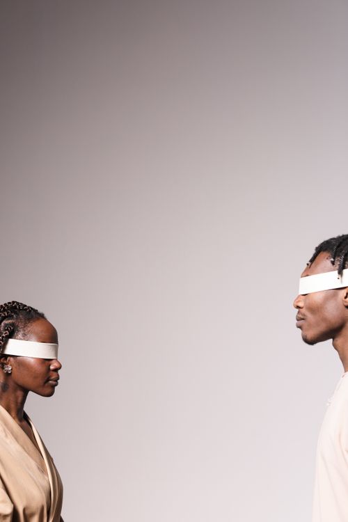 Free Two blindfolded people facing each other in a studio with a neutral background. Stock Photo