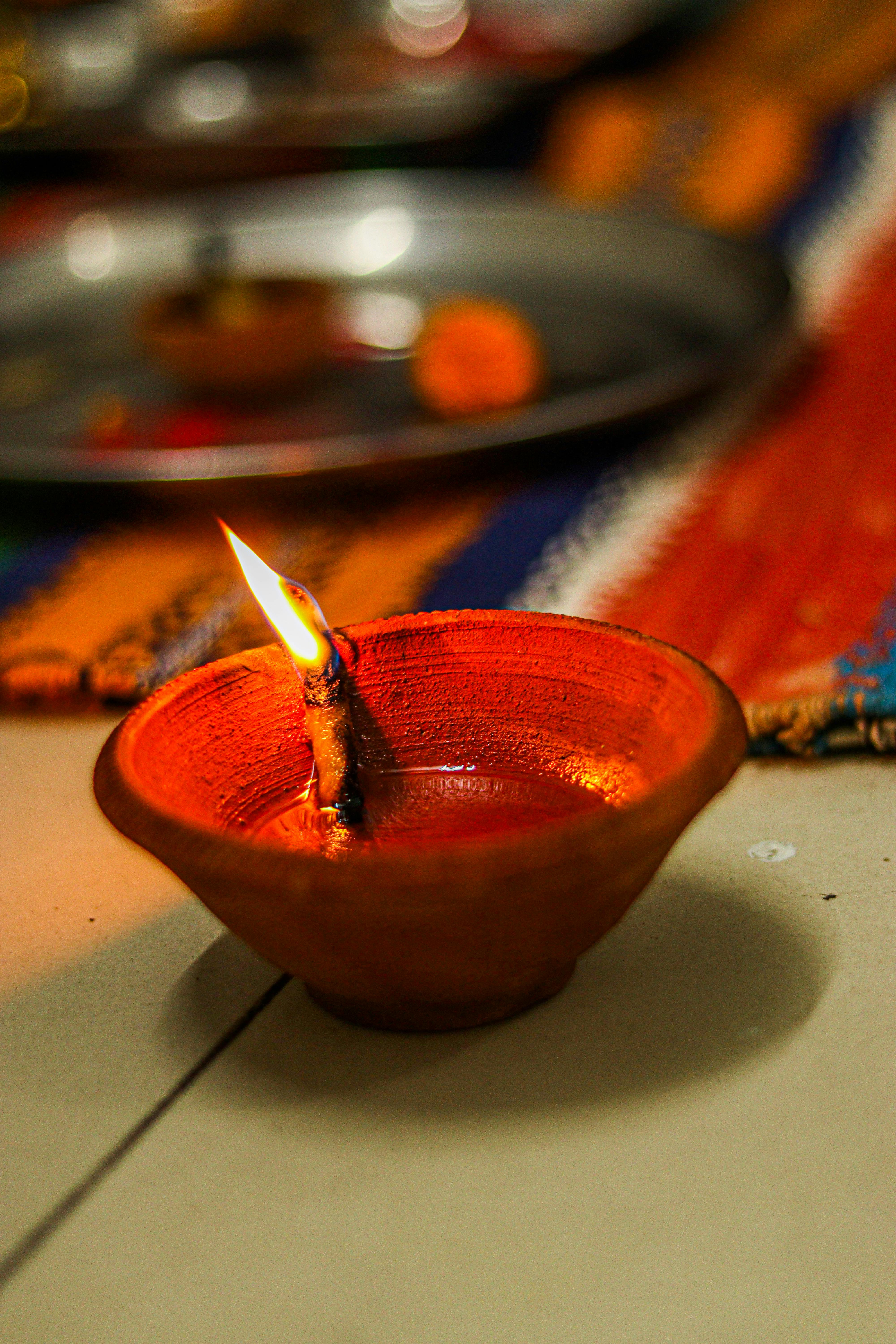 A close-up of a traditional clay diya lamp with a burning flame, symbolizing warmth and light.