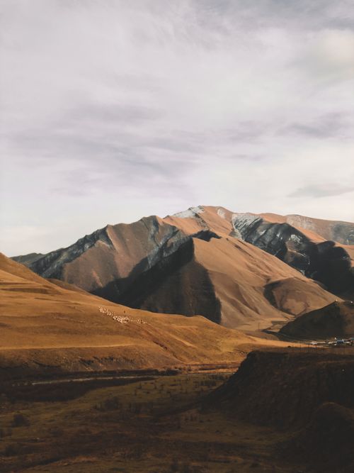 Free Serene view of a mountain range with earthy tones under a cloudy sky, captivating scenery. Stock Photo