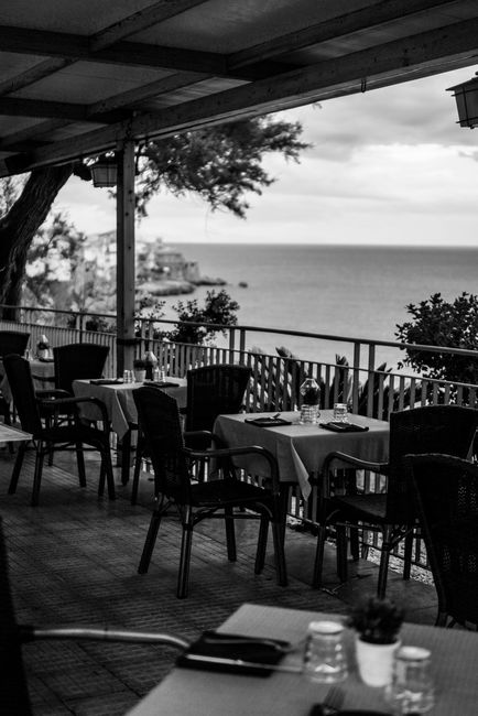 Photo by Anna Shakhrai on Pexels Elegant al fresco dining on a seaside terrace with a stunning ocean view in black and white.