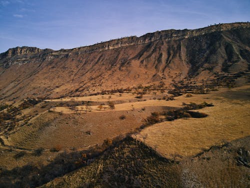 Brown Mountain on Desert Land Under Blue Sky