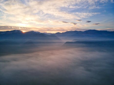 Serene mountain landscape at sunrise with fog-filled valleys and a vibrant sky.. serene, mountain, landscape