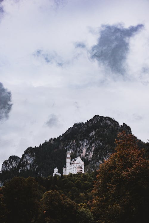 White Castle in the Middle of a Mountain Under a Cloudy Sky