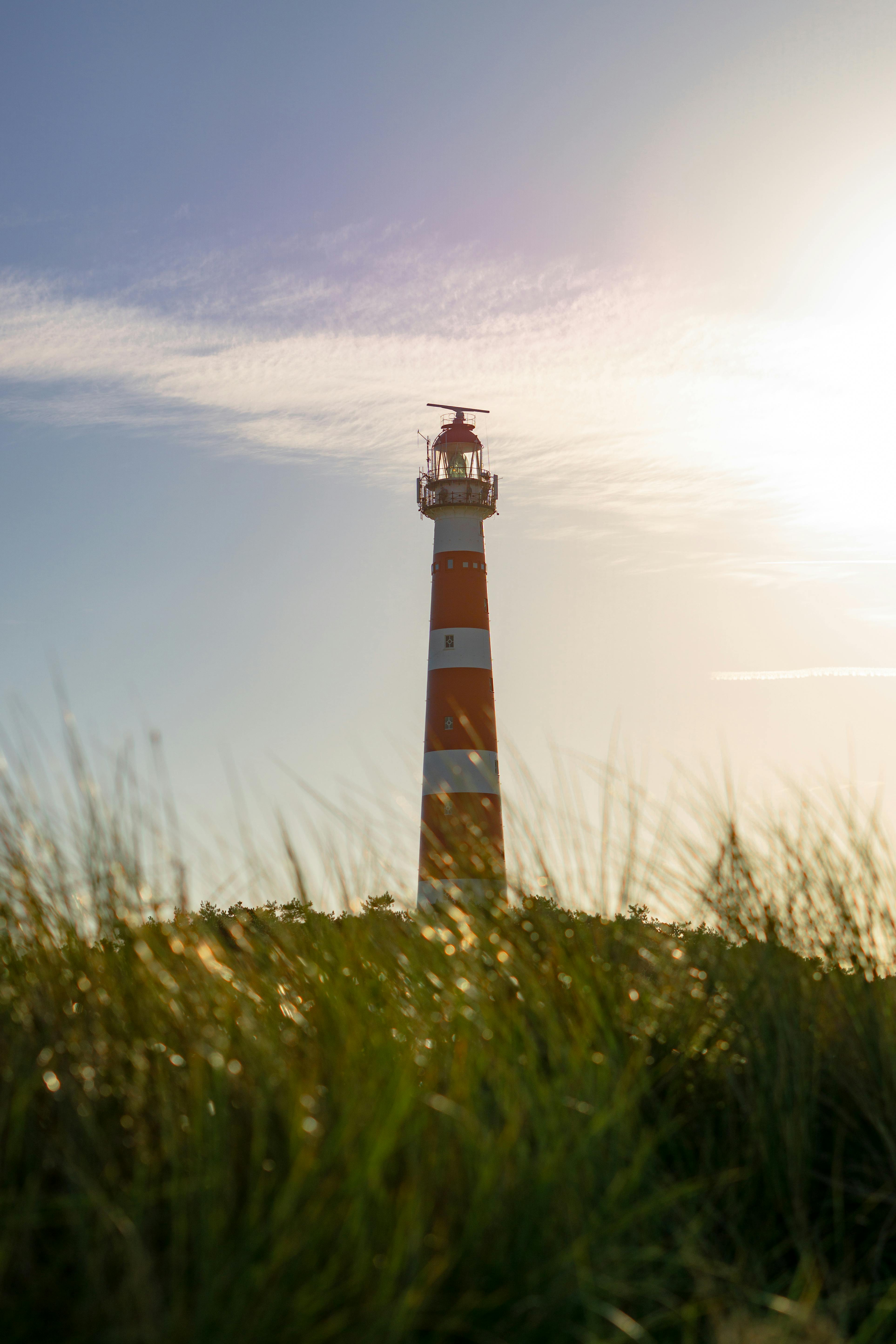 Red and Yellow Lighthouse on a Grassy Field · Free Stock Photo