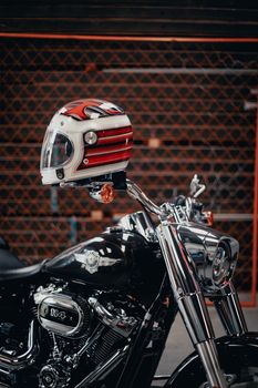 Chrome Harley Davidson with red and white helmet in front of a metal fence in Curitiba.