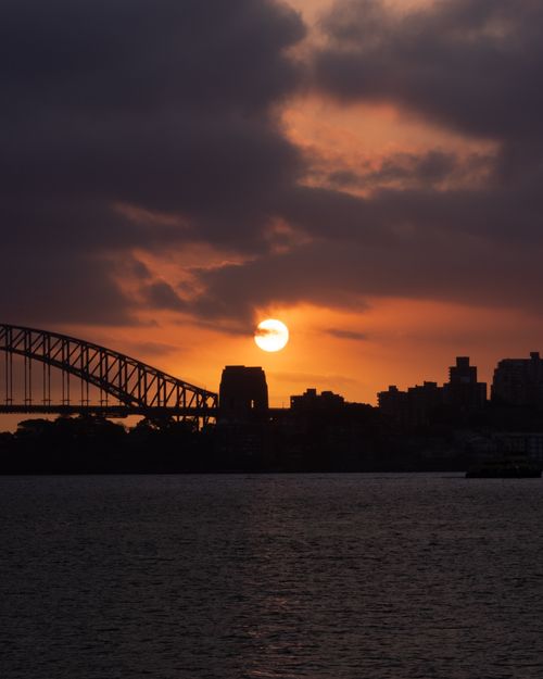 Free Captivating sunset view of Sydney Harbour Bridge silhouette against a dramatic sky. Stock Photo
