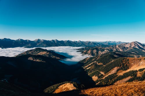 Aerial View of Mountains and Trees Under Blue Sky 