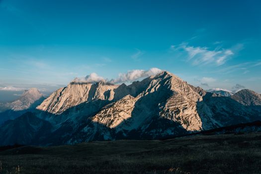 Beautiful mountain landscape with sunlight and clouds highlighting the peaks at sunrise.