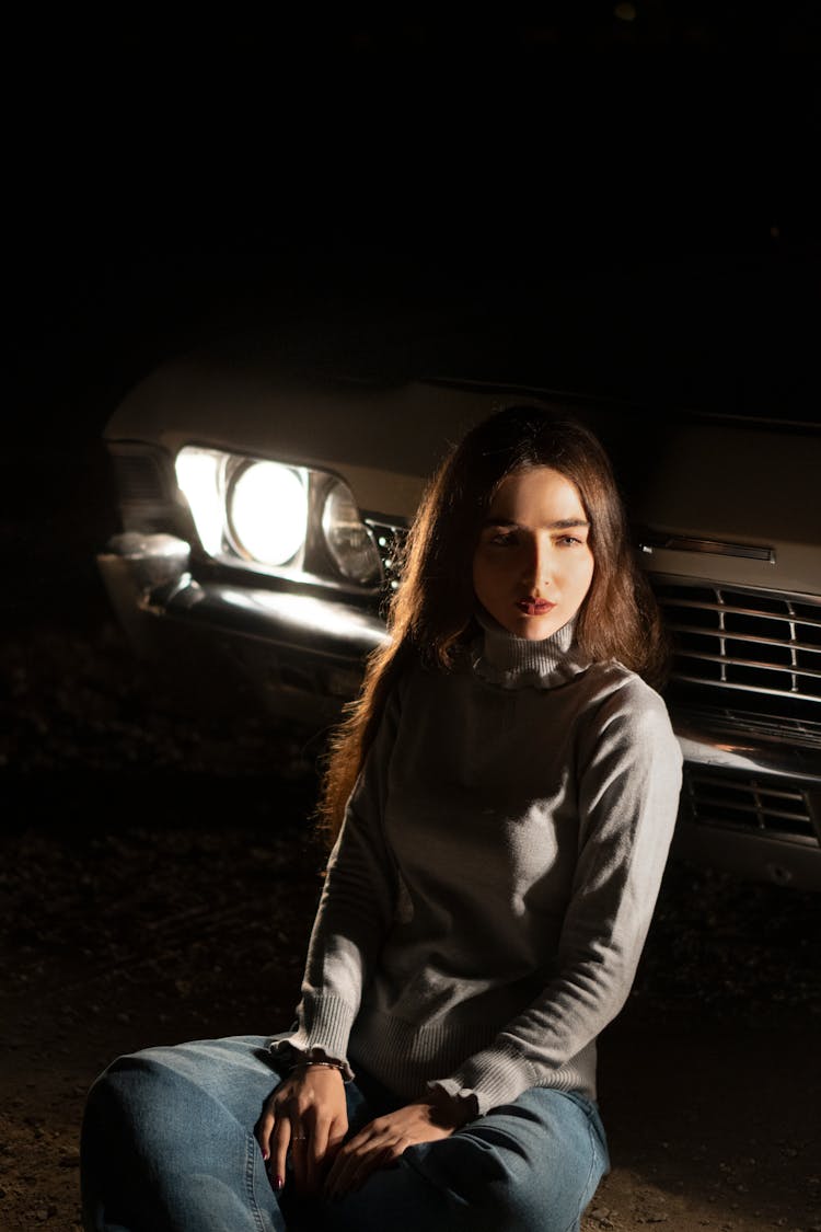 Woman Sitting Near Car With Turned On Lamps