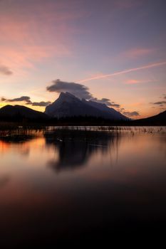 Serene sunset view of a lake with mountain reflections in Banff National Park, Canada.
