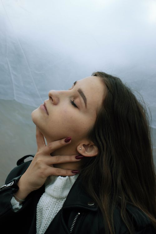 Free Elegant portrait of a woman in a leather jacket, eyes closed, with serene expression. Stock Photo