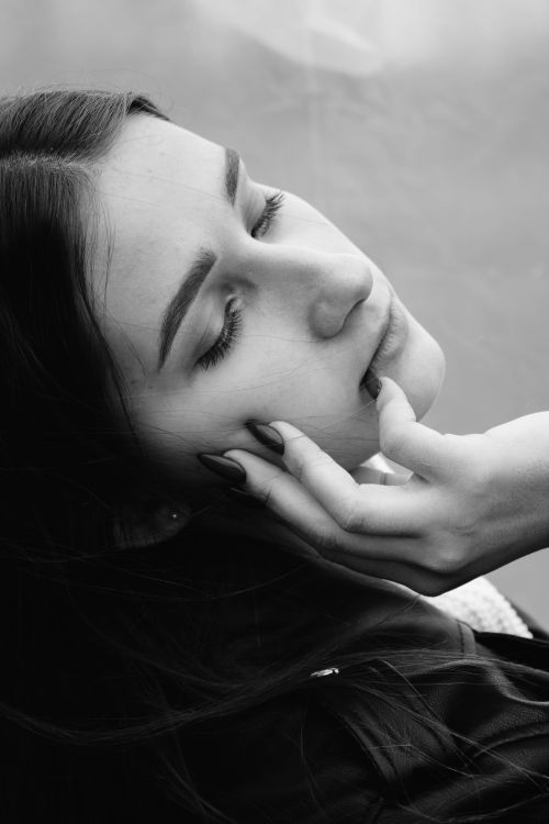 Free Stylish black and white portrait featuring a woman with eyes closed, hand on face. Stock Photo