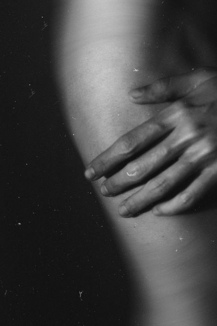 Close-up black and white image of a hand touching skin, conveying intimacy and texture.