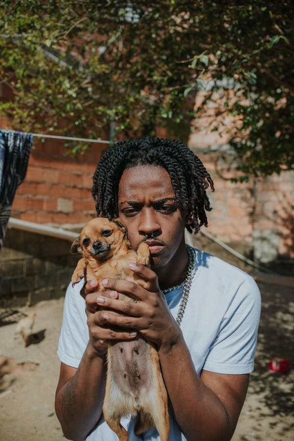A Man with Braided Hair Holding Dog