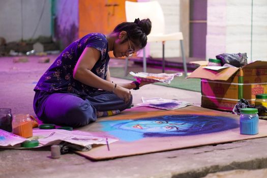 A young artist focused on creating a vibrant chalk portrait indoors.