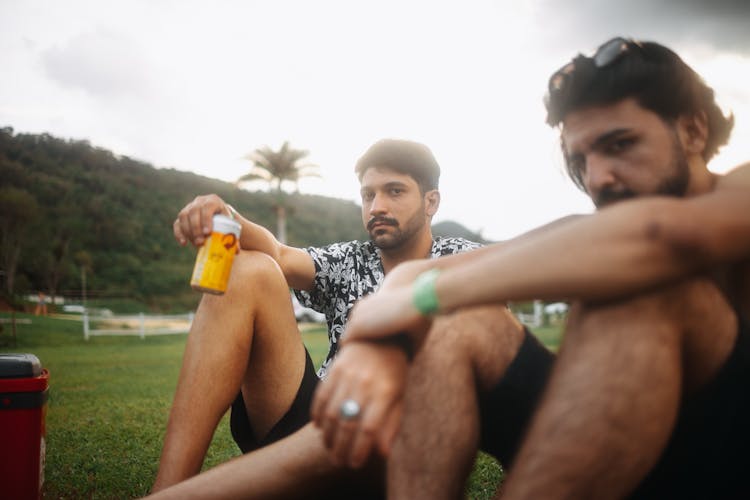 Men Sitting On Ground With Beer