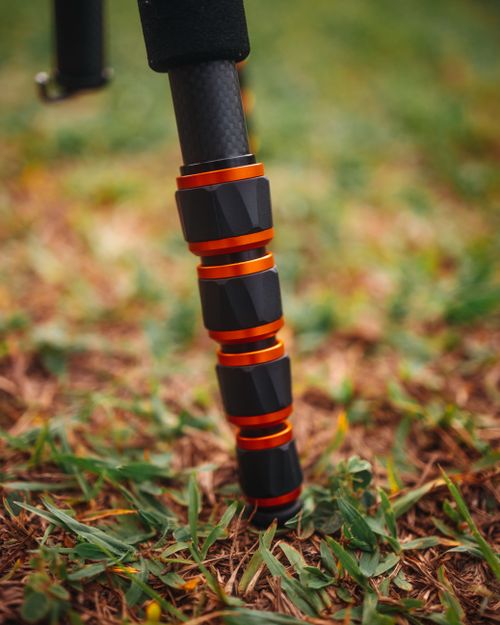Free Close-up view of a carbon fiber tripod leg standing on grassy ground. Stock Photo