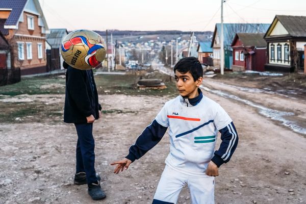 Two boys playing soccer together on a sunny day