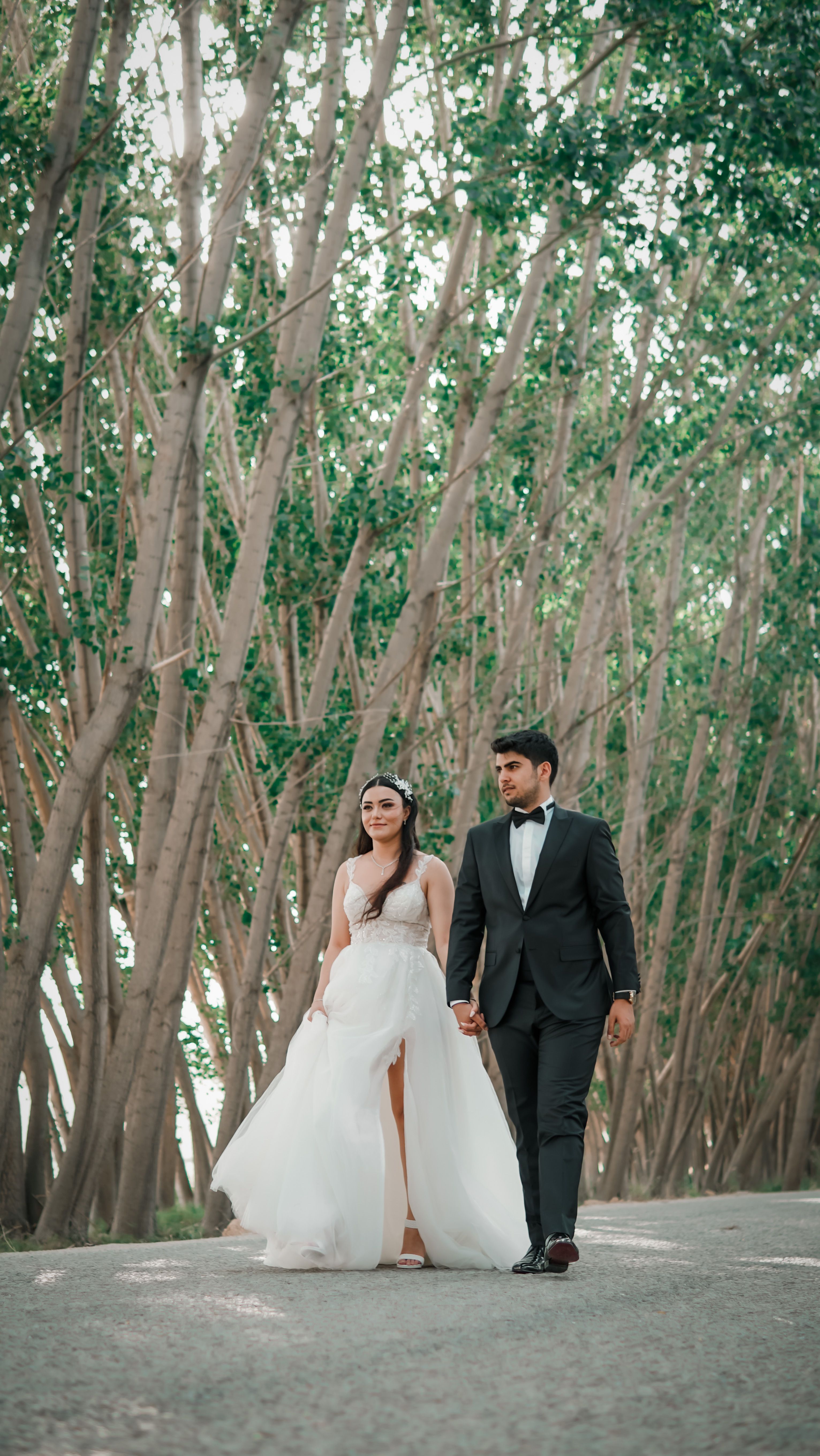 Bride and groom hand-in-hand amidst a tranquil outdoor setting, exuding elegance and romance.