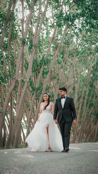 Bride and groom hand-in-hand amidst a tranquil outdoor setting, exuding elegance and romance.