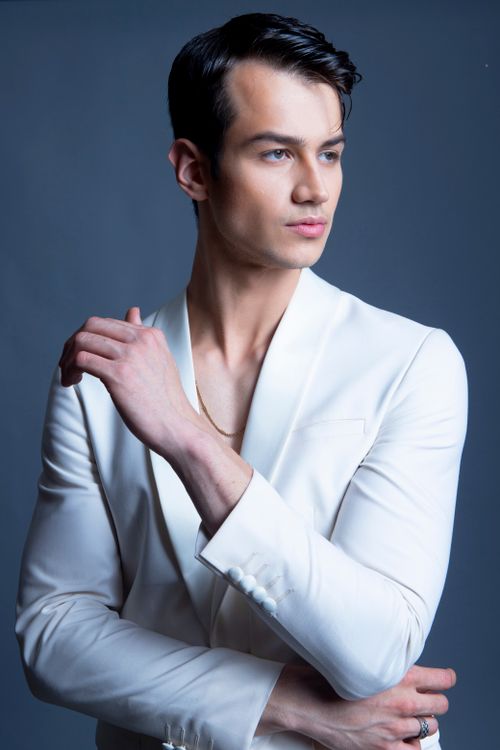 Free Stylish portrait of an elegant male model in a white suit with a serious expression. Stock Photo
