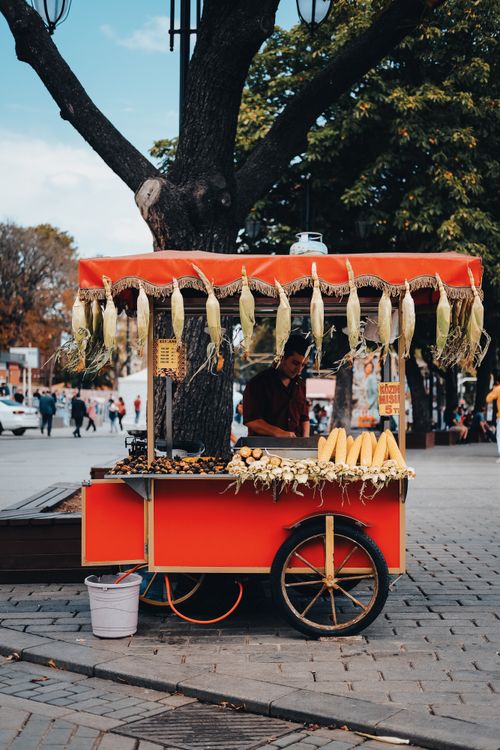 Free A vibrant red cart with corn and a vendor at an Istanbul street market. Stock Photo