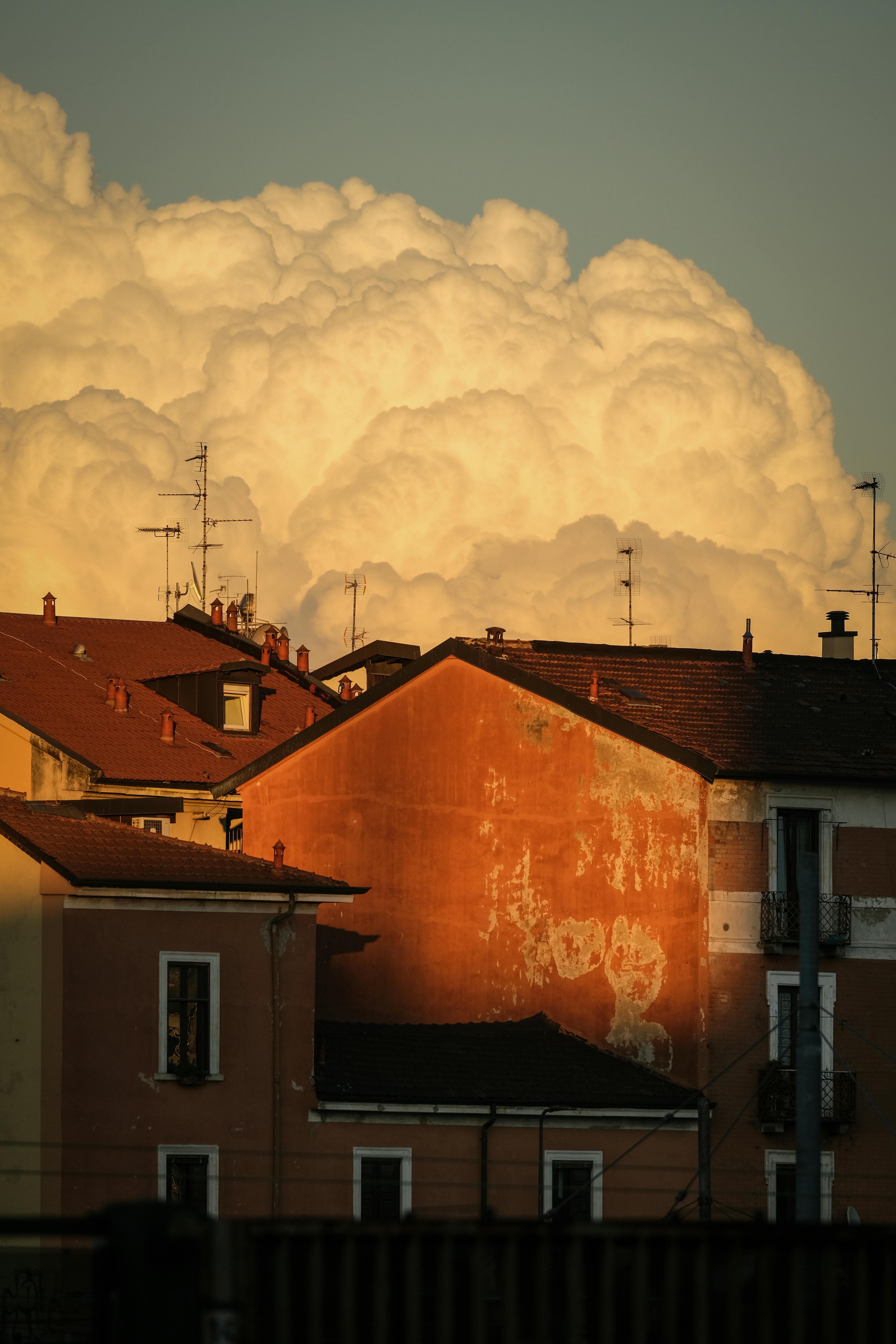 A nostalgic view of European building rooftops against dramatic sunset clouds.