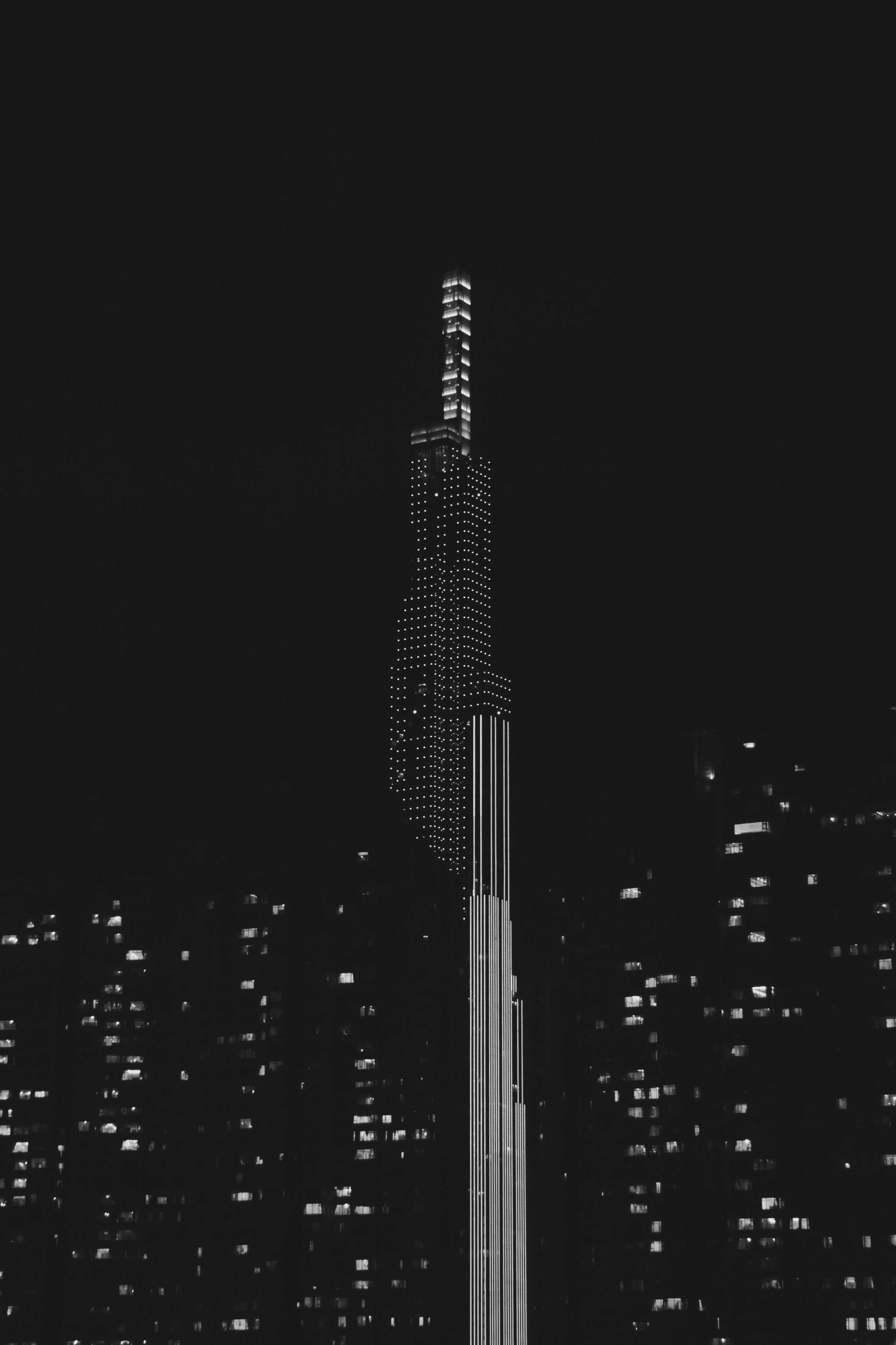 Grayscale photograph of a city tower illuminated at night.