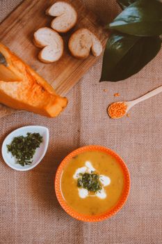 Delicious pumpkin soup served with bread and herbs. Perfect for a cozy autumn meal.