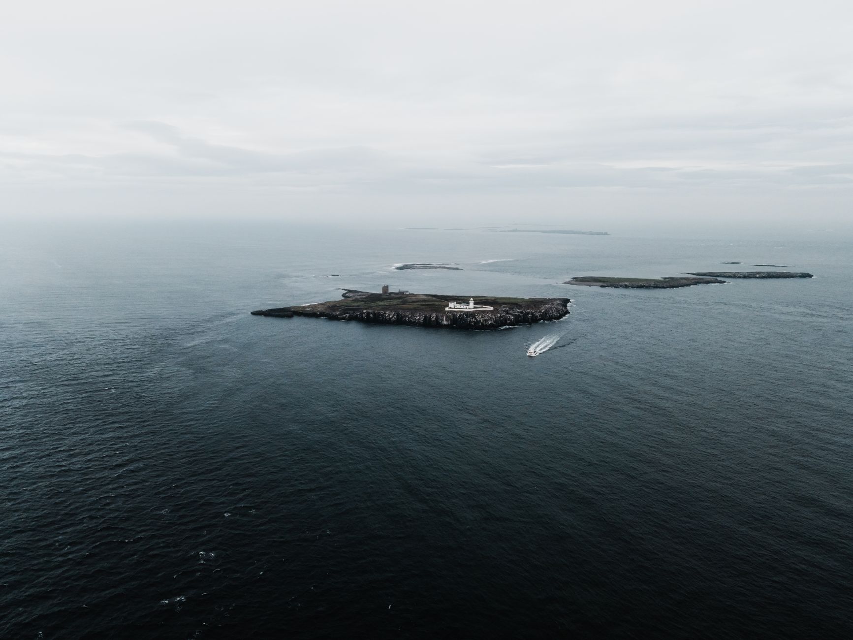 Drone shot capturing the serene Farne Islands and lighthouse in the UK sea.