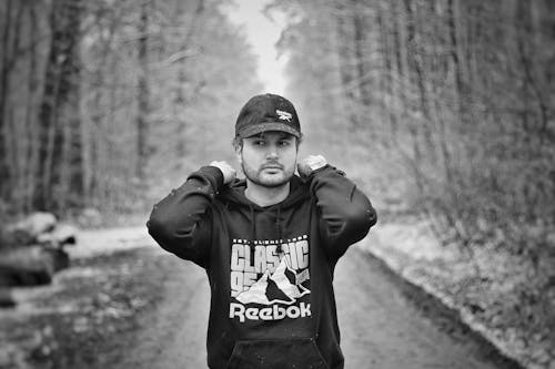 A Grayscale of a Man Wearing a Cap and a Hoodie