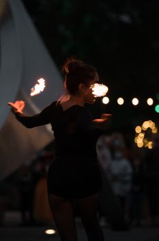 A captivating fire dancer performs an evening show with glowing flames and dynamic movements.