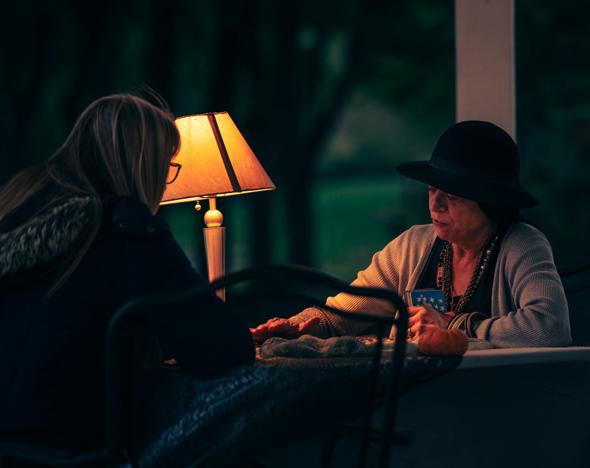 A mysterious tarot reading session between a fortune teller and a woman at night.