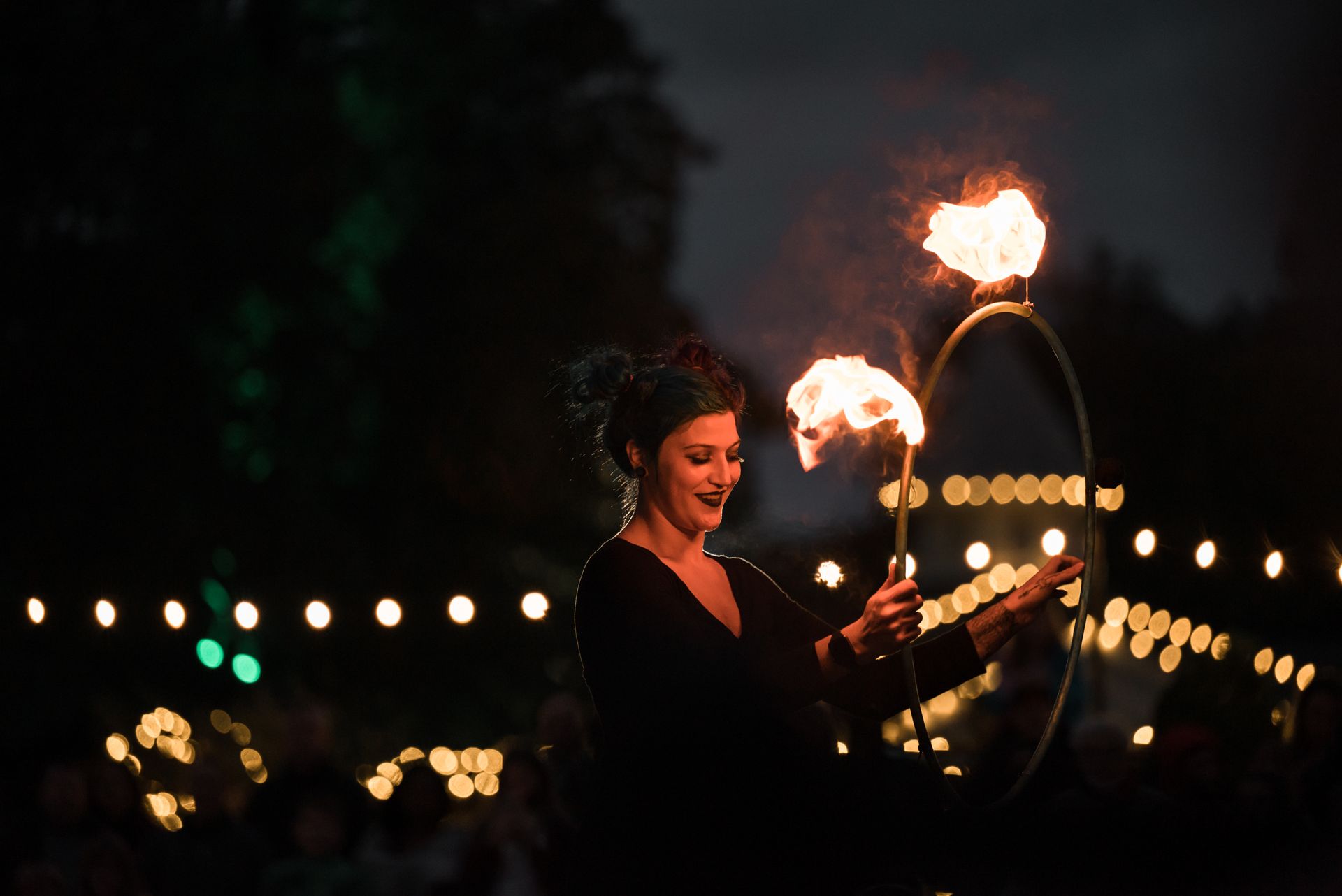 A captivating woman performs fire tricks at a nighttime outdoor event.