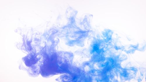 Free Vibrant blue and purple smoke swirling creatively on a white backdrop. Stock Photo