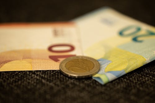 A Coin and Paper Bills in Close-up Shot