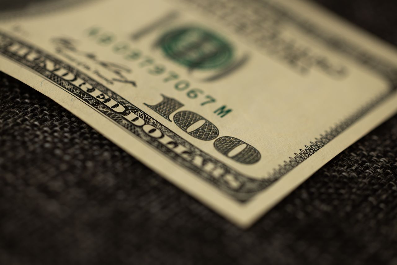 detailed close up of a hundred dollar bill resting on dark fabric surf