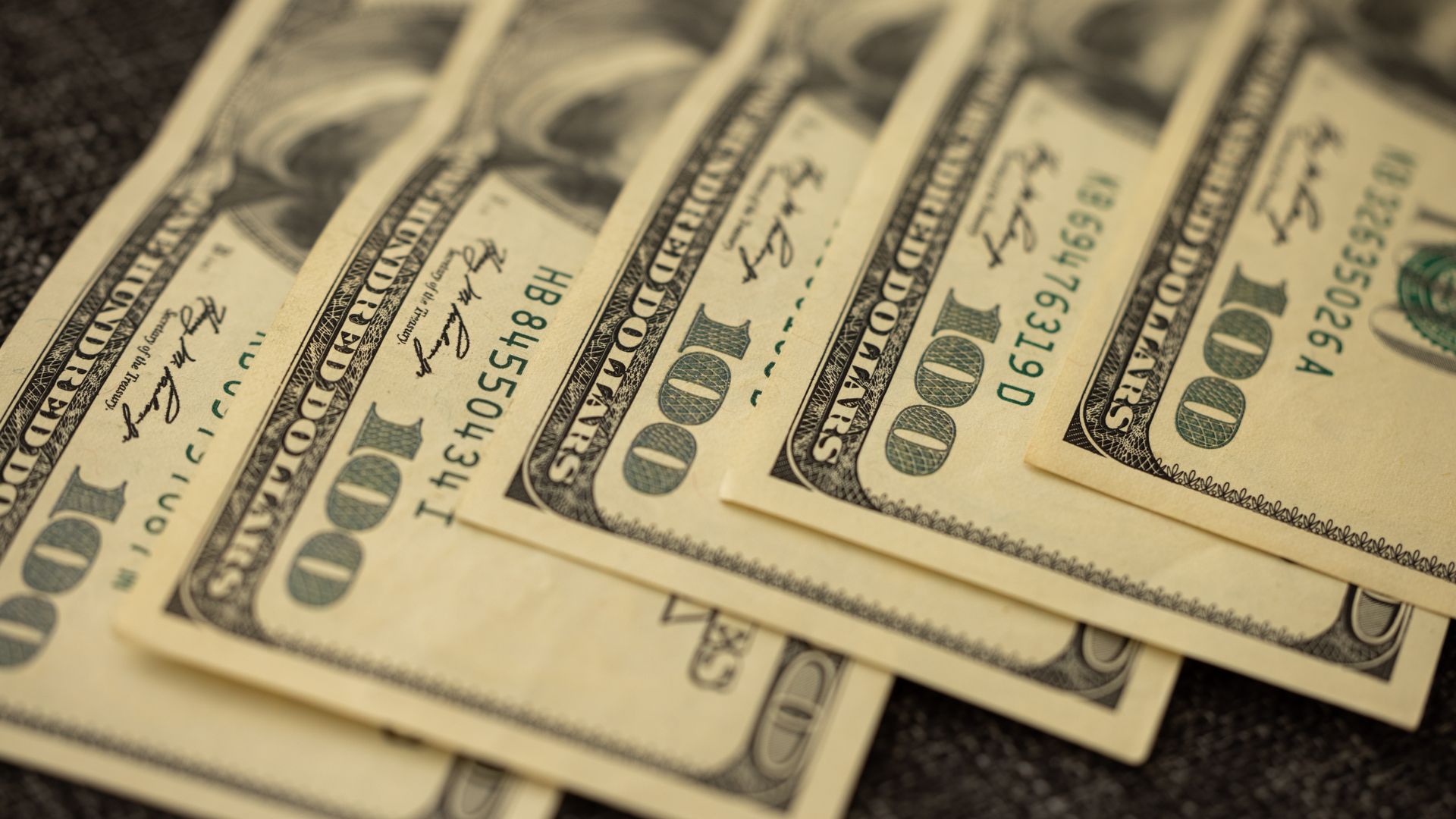 A detailed view of stacked US hundred dollar bills in a close-up shot — qdte dividend history