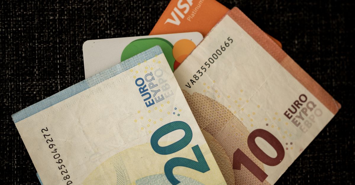 Close-up of euro banknotes and credit cards on a dark textured surface.