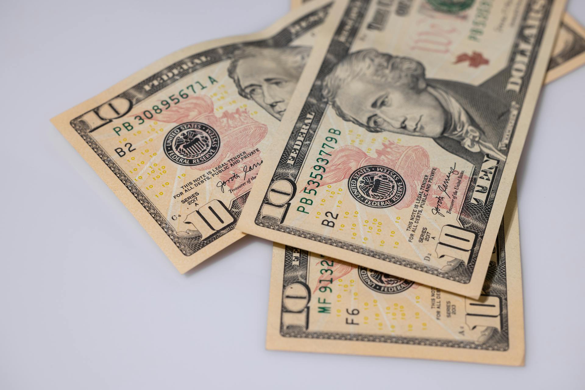 Detailed view of American ten dollar bills scattered on a light surface, showcasing currency features.