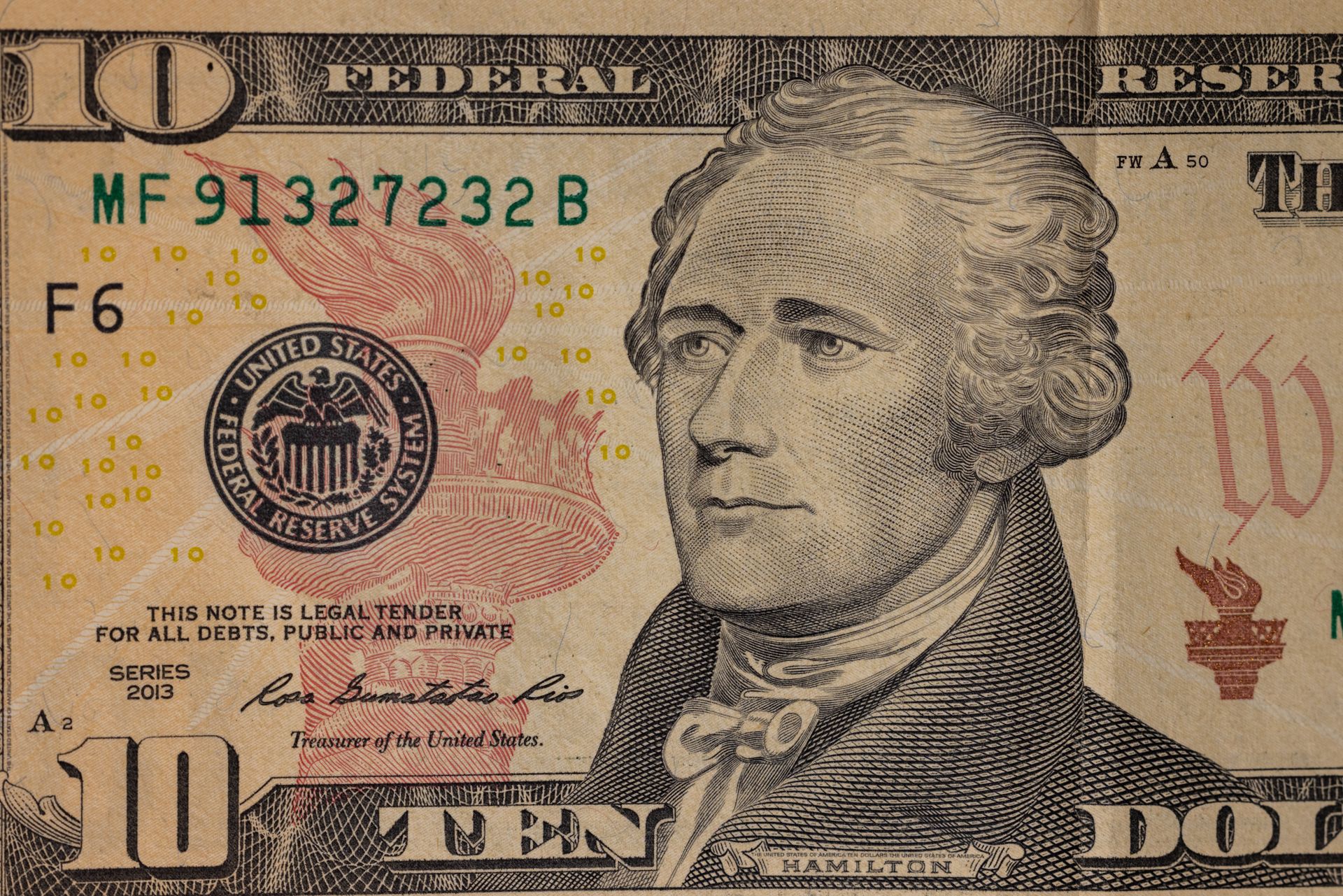 Detailed close-up image of a US ten dollar bill with Alexander Hamilton's portrait.