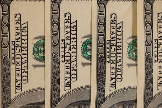 Detailed close-up of multiple US hundred dollar bills, showcasing currency design.