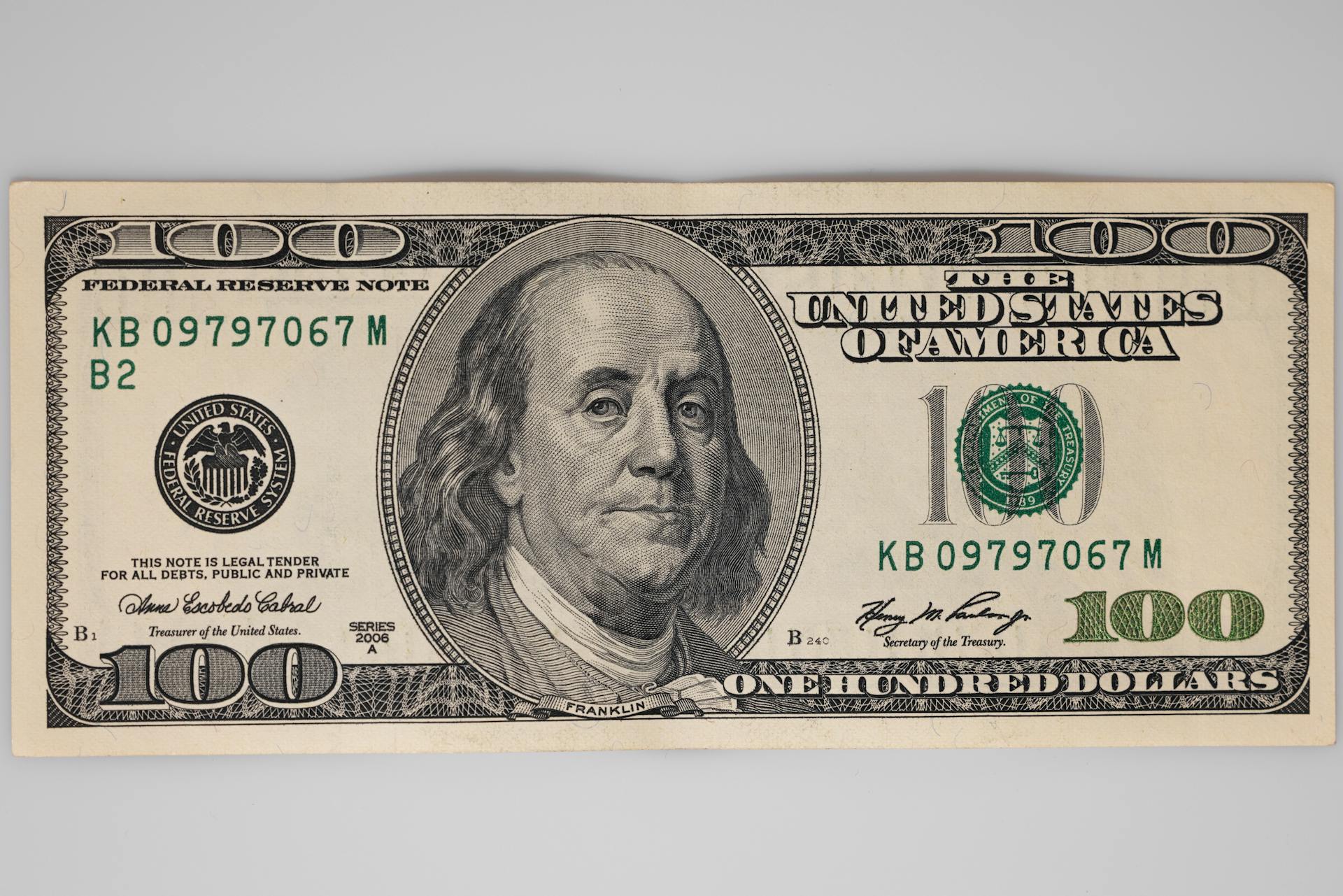 A detailed close-up of a US $100 bill featuring Benjamin Franklin on a white background.