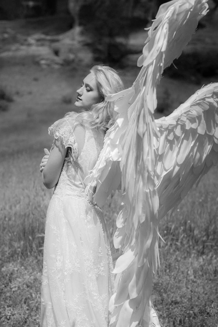 Girl Posing In Field In White Dress And Angel Wings