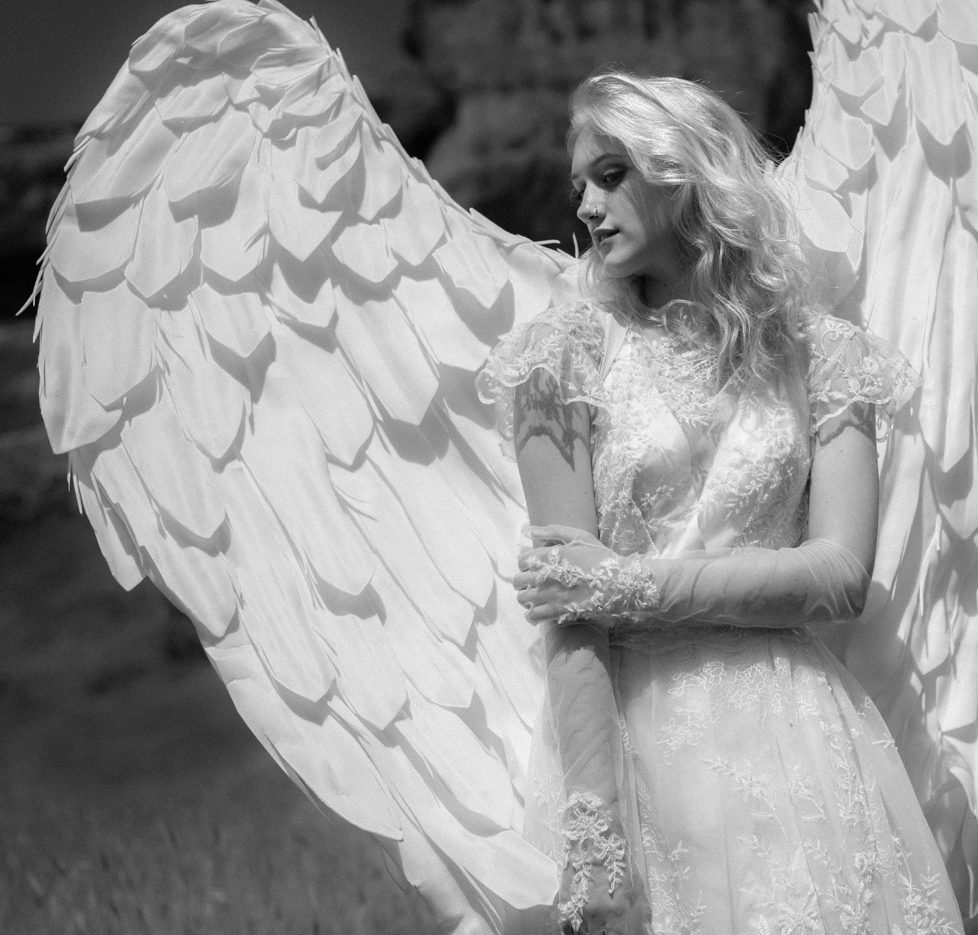 Black and white portrait of a woman in an angel costume with large wings.